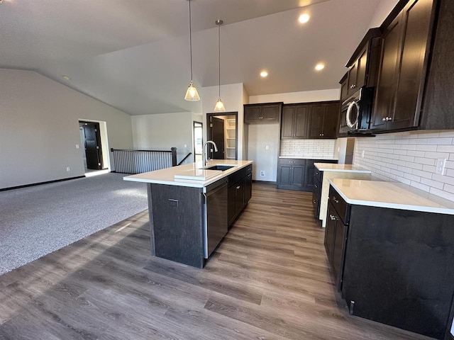 kitchen with stainless steel appliances, an island with sink, sink, hanging light fixtures, and backsplash