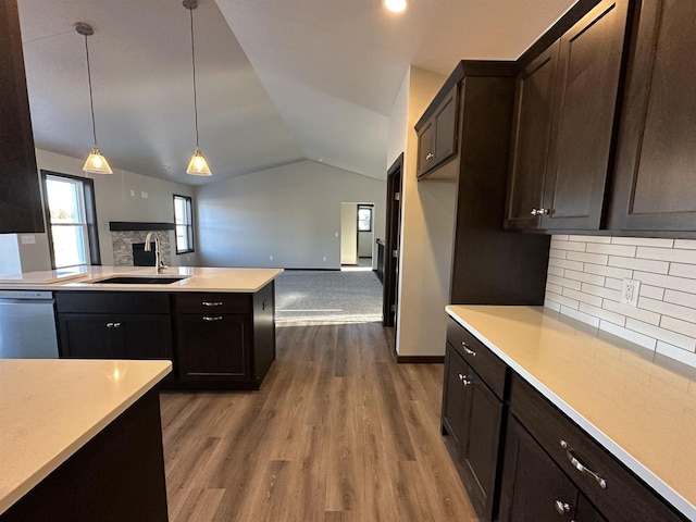 kitchen with backsplash, dishwasher, hanging light fixtures, vaulted ceiling, and sink