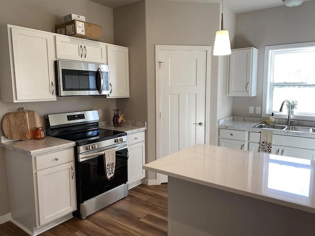 kitchen featuring sink, pendant lighting, stainless steel appliances, and white cabinetry