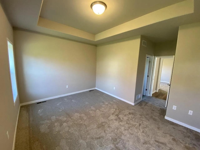 carpeted spare room with a raised ceiling