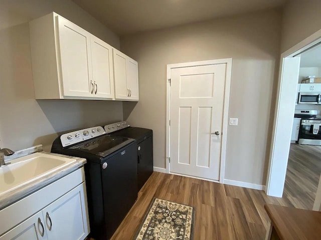 laundry room with washing machine and dryer, cabinets, light hardwood / wood-style floors, and sink