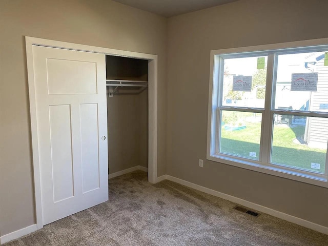 unfurnished bedroom featuring light carpet, a closet, and multiple windows