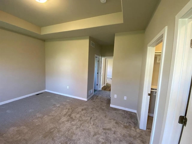 carpeted spare room featuring a raised ceiling