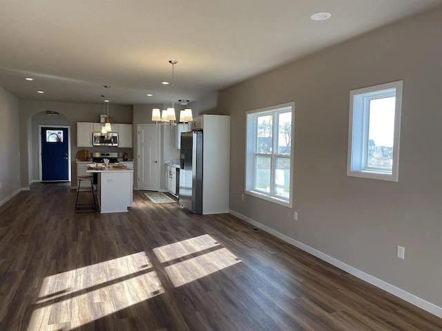 kitchen featuring pendant lighting, a center island, white cabinetry, stainless steel appliances, and a kitchen breakfast bar