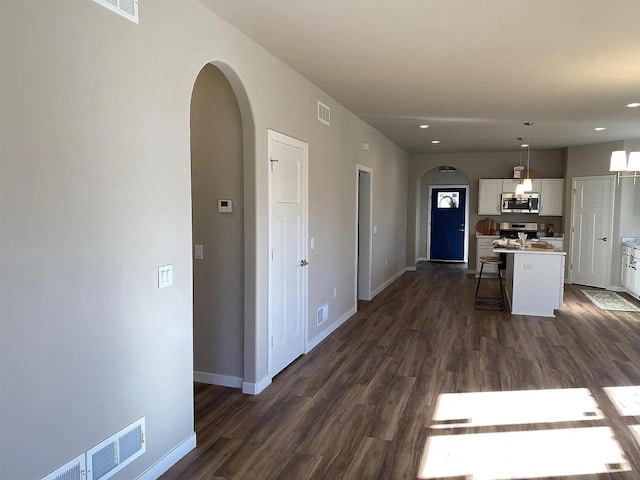 kitchen with a breakfast bar area, appliances with stainless steel finishes, pendant lighting, white cabinets, and a center island