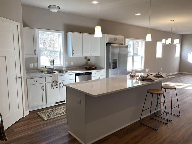 kitchen featuring a center island, sink, stainless steel appliances, and white cabinetry