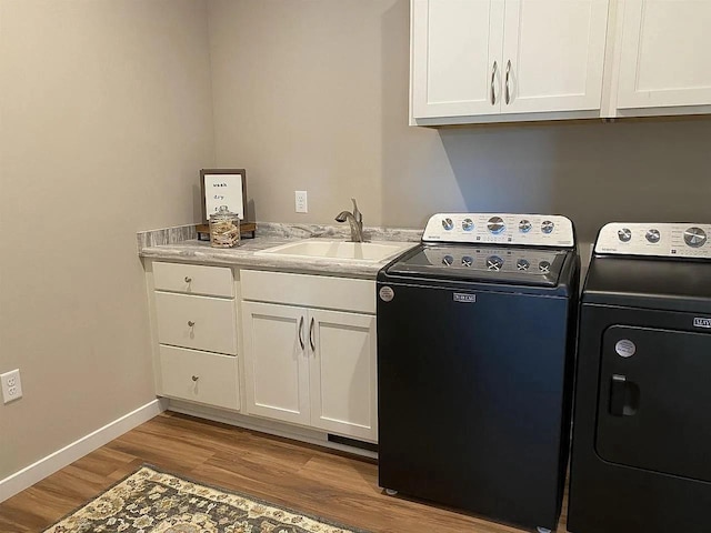 laundry room featuring cabinets, washer and dryer, light hardwood / wood-style floors, and sink