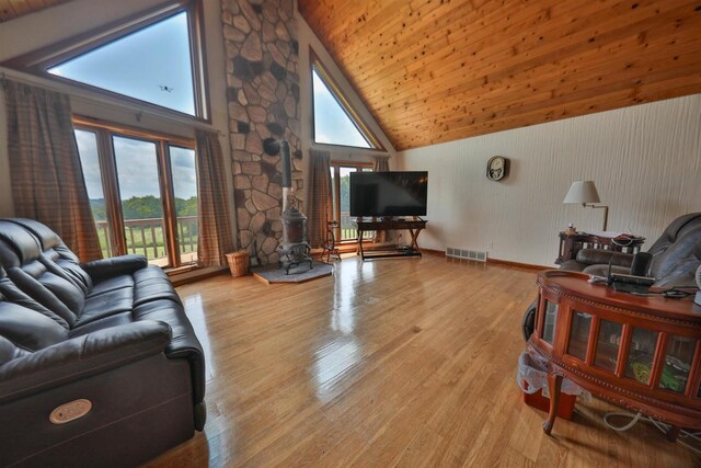 living room featuring high vaulted ceiling, a wood stove, wood ceiling, and light hardwood / wood-style floors