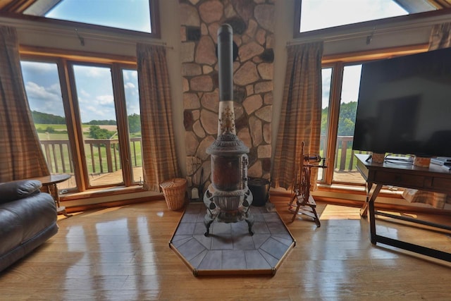 living room featuring a wood stove, a towering ceiling, and hardwood / wood-style floors