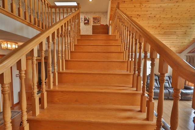 staircase with wooden ceiling, wood-type flooring, a chandelier, and vaulted ceiling