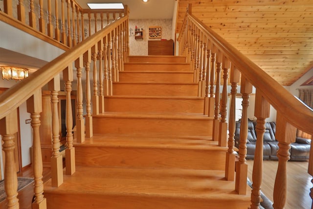 stairs with wood ceiling, light wood-type flooring, and a towering ceiling