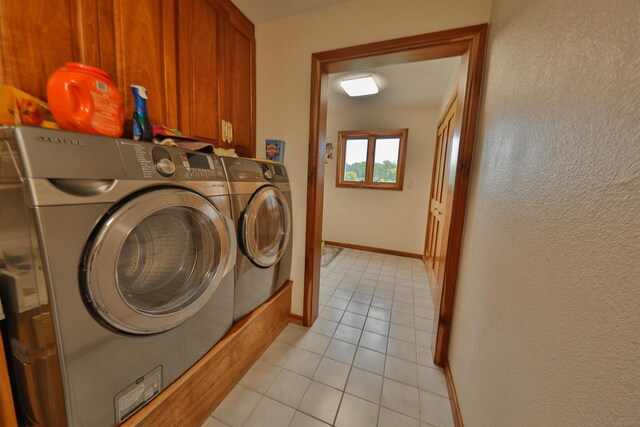 washroom with light tile patterned floors, cabinets, and washer and dryer