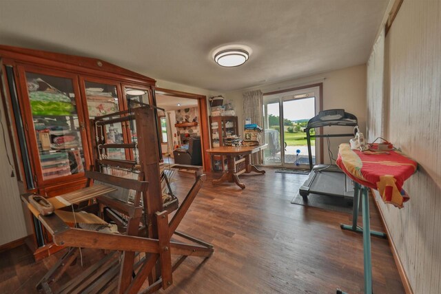 living room featuring ceiling fan, a stone fireplace, and dark wood-type flooring