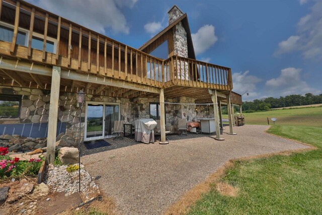 rear view of property featuring a patio area, a wooden deck, and a yard