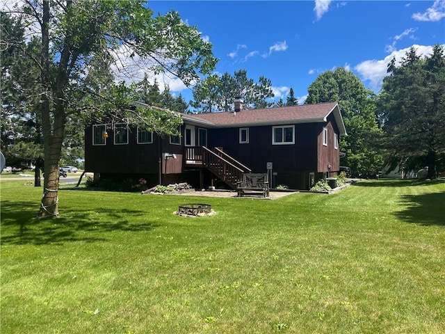 rear view of house with a lawn and a fire pit