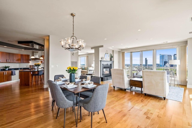 dining area with light wood-type flooring and an inviting chandelier