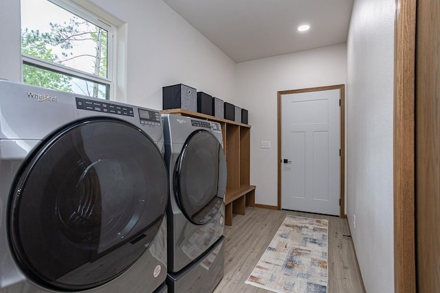 laundry area featuring washing machine and dryer and light hardwood / wood-style flooring