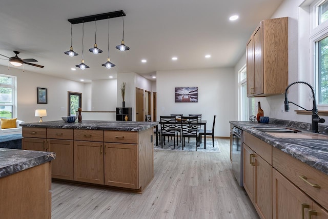 kitchen featuring decorative light fixtures, ceiling fan, dishwasher, light hardwood / wood-style floors, and sink