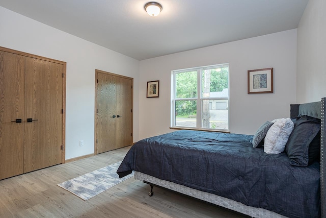 bedroom with multiple closets and light hardwood / wood-style floors