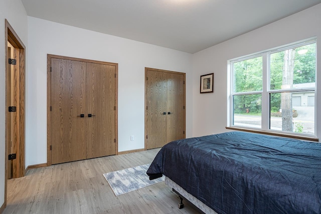 bedroom with multiple closets and light hardwood / wood-style flooring