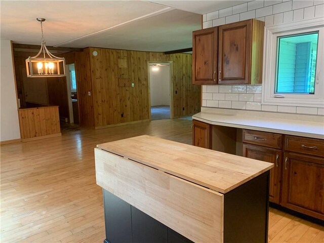 kitchen with a notable chandelier, a kitchen island, butcher block countertops, hanging light fixtures, and light wood-type flooring