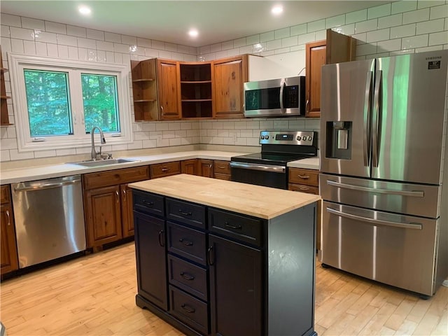 kitchen with appliances with stainless steel finishes, a kitchen island, wood counters, decorative backsplash, and sink