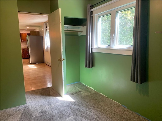 interior space with light colored carpet and a baseboard heating unit