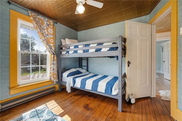 bedroom featuring hardwood / wood-style flooring, ceiling fan, and baseboard heating