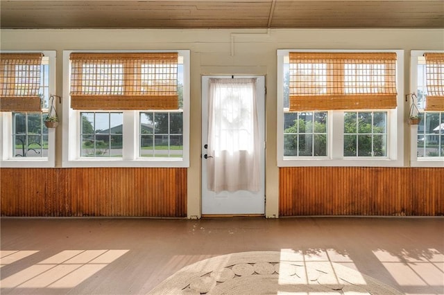 doorway to outside with wooden ceiling and wood walls