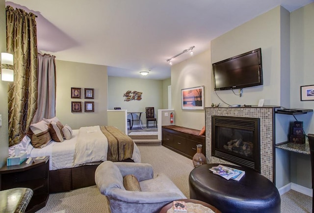 carpeted bedroom with track lighting and a tiled fireplace