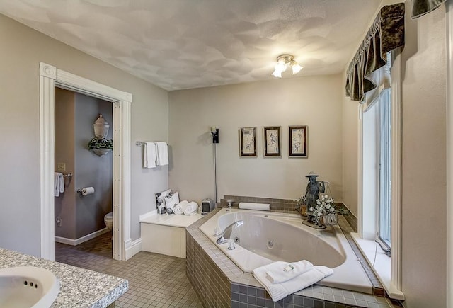 bathroom featuring toilet, vanity, tile patterned floors, and a relaxing tiled tub