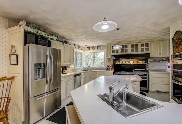 kitchen featuring sink, pendant lighting, stainless steel appliances, and cream cabinets