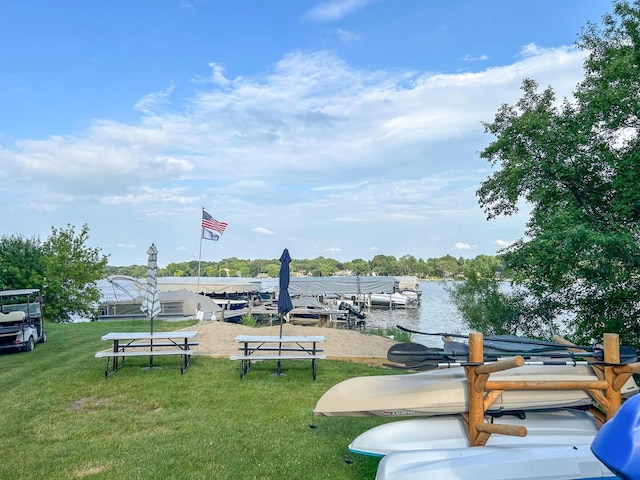 view of community featuring a water view, a dock, and a lawn