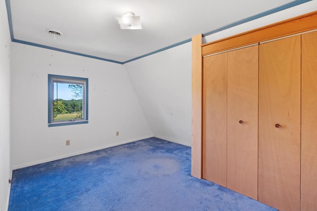 unfurnished bedroom with a closet, lofted ceiling, and dark colored carpet