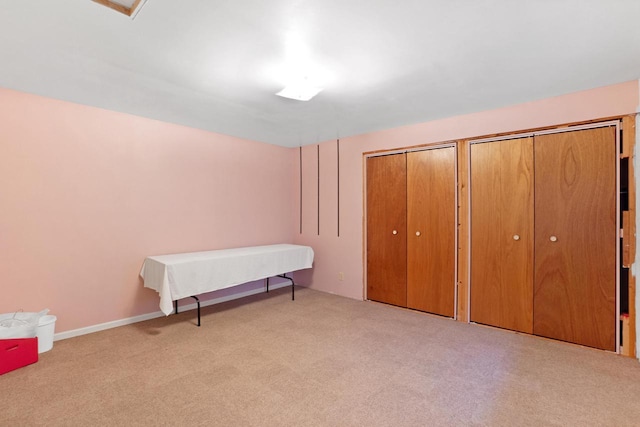 unfurnished bedroom with two closets and light colored carpet