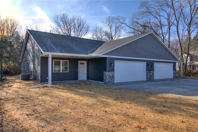 single story home with central AC unit, a front lawn, and a garage