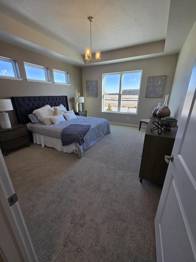 carpeted bedroom featuring a chandelier and a tray ceiling