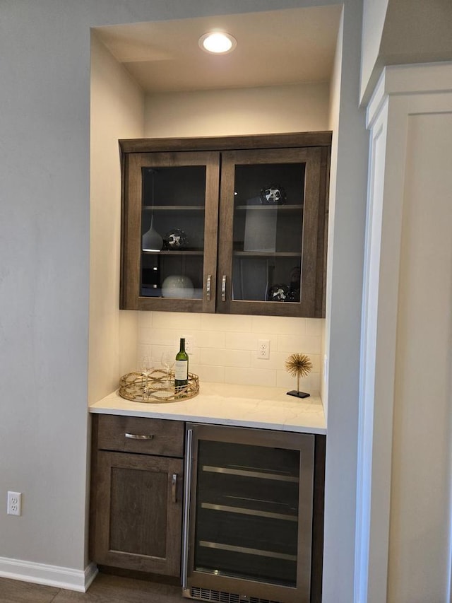 bar with decorative backsplash, dark brown cabinetry, and wine cooler