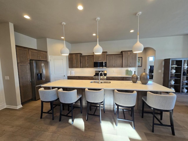 kitchen featuring hanging light fixtures, a large island with sink, appliances with stainless steel finishes, and sink