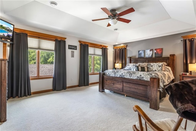 bedroom with a raised ceiling, light colored carpet, and ceiling fan