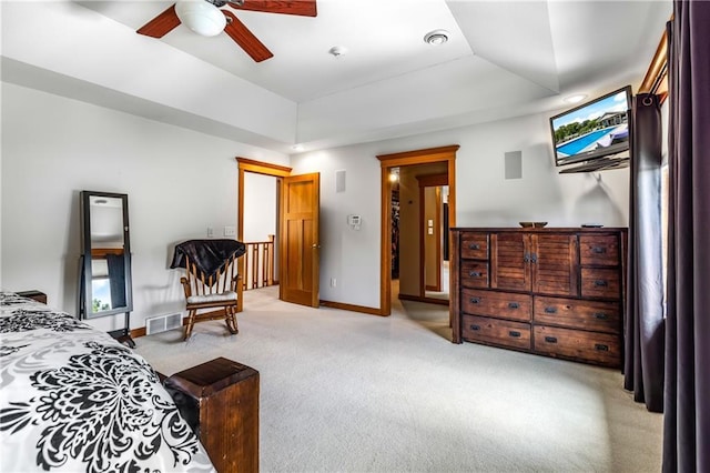 carpeted bedroom with a raised ceiling and ceiling fan