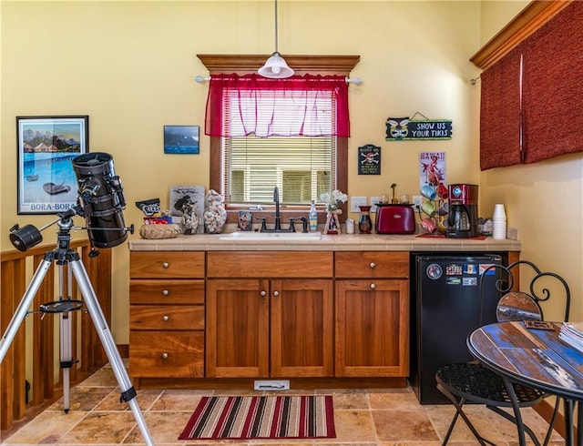 kitchen featuring pendant lighting, tile countertops, dishwasher, and sink