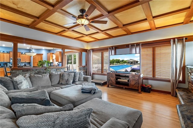 living room with beam ceiling, coffered ceiling, ceiling fan, and light hardwood / wood-style flooring