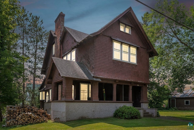 back house at dusk featuring a lawn