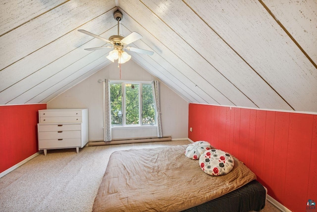 unfurnished bedroom with lofted ceiling, wood walls, ceiling fan, and carpet