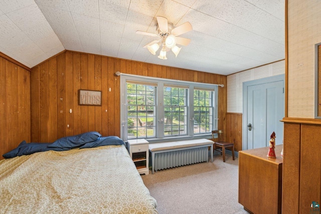 carpeted bedroom featuring lofted ceiling, radiator heating unit, ceiling fan, and wood walls