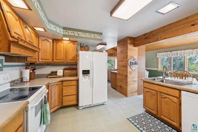 kitchen featuring white appliances, sink, decorative backsplash, and wood walls