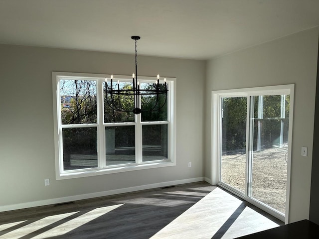 unfurnished dining area with an inviting chandelier and dark hardwood / wood-style flooring