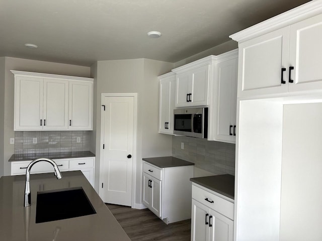 kitchen with white cabinetry, dark wood-type flooring, sink, and decorative backsplash