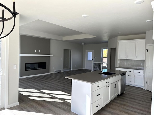 kitchen with sink, white cabinets, decorative backsplash, a kitchen island with sink, and stainless steel dishwasher